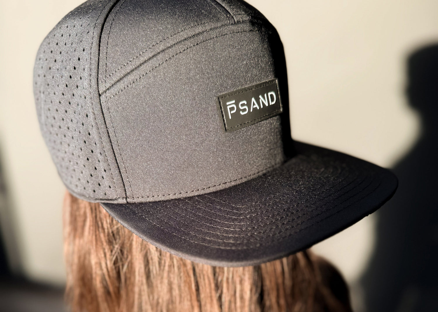 Person wearing a black hat with 'PSAND' logo on a blurred background